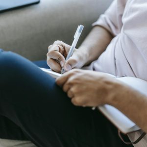 Crop unrecognizable person writing in diary