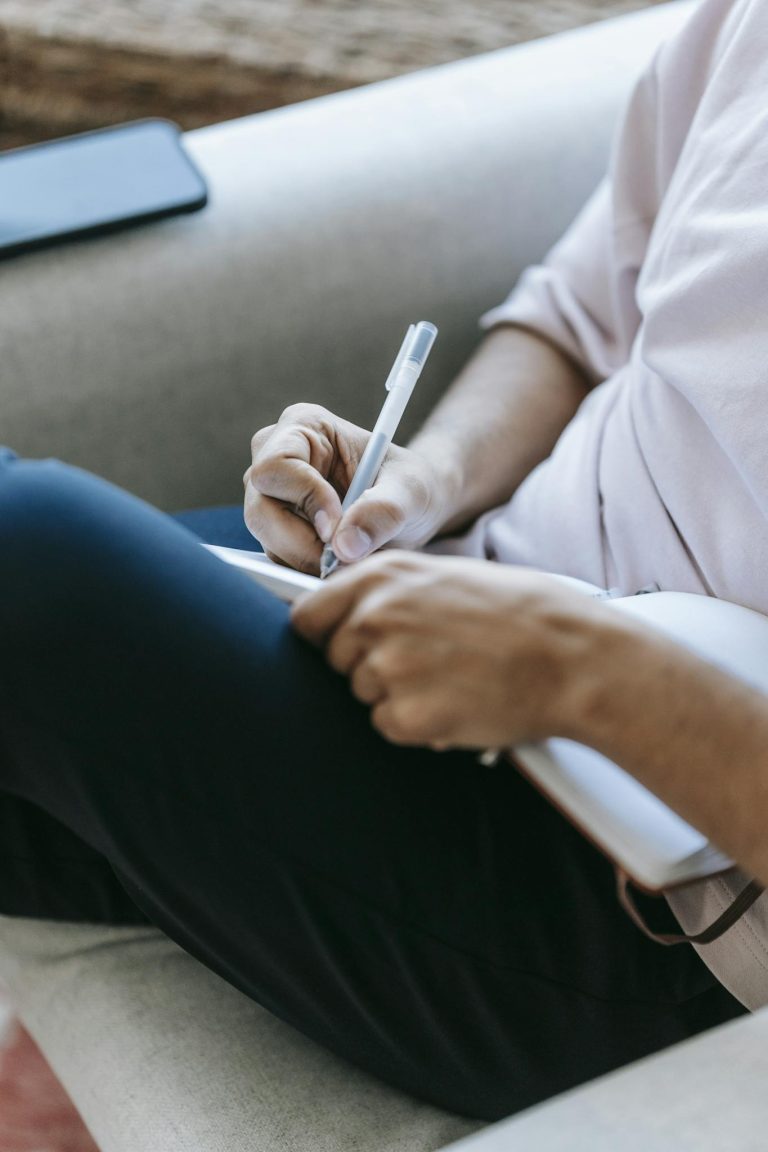 Crop unrecognizable person writing in diary